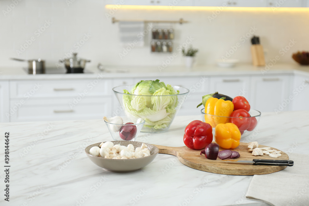 Poster Different fresh vegetables and mushrooms on white table in modern kitchen