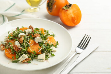 Delicious persimmon salad served on white wooden table, closeup