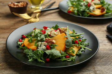 Delicious persimmon salad with pomegranate and arugula served on wooden table
