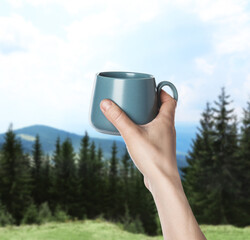 Closeness to nature. Woman holding cup in mountains, closeup