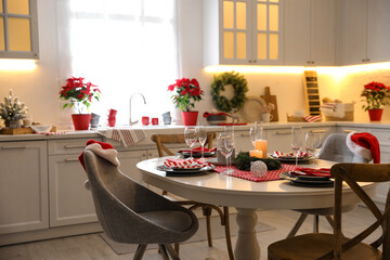 Table with dishware in beautiful kitchen interior decorated for Christmas