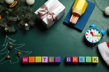 Fototapeta na wymiar Colorful cubes with text Winter Break and Christmas decor on green background, flat lay. School holidays