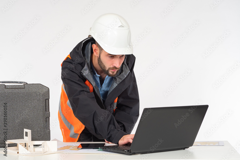 Poster architect engineer uses a laptop. man in a builder's uniform is typing something. he stands next to 