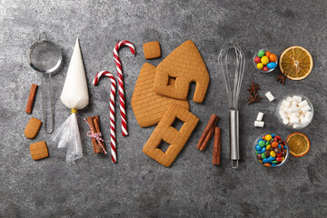 Parts of gingerbread house, kitchenware and ingredients for decoration on grey table, flat lay