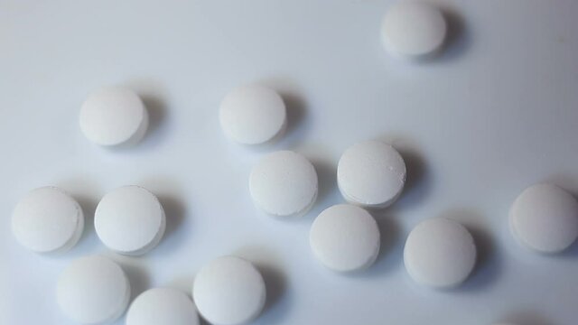 The man scoops up small white round pills with his hand. On a white background, close-up, contains people, real time, medicine, health