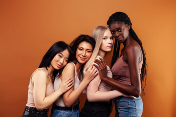 young pretty asian, caucasian, afro woman posing cheerful together on brown background, lifestyle diverse nationality people concept