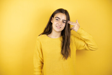 Pretty girl wearing a yellow sweater standing over isolated yellow background Shooting and killing oneself pointing hand and fingers to head like gun, suicide gesture.
