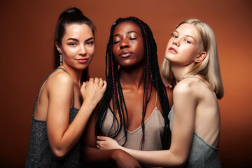 young pretty asian, caucasian, afro woman posing cheerful together on brown background, lifestyle diverse nationality people concept