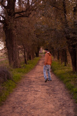 Fototapeta na wymiar young man in the forest at autumn with a yellow hoodie and blue jeans