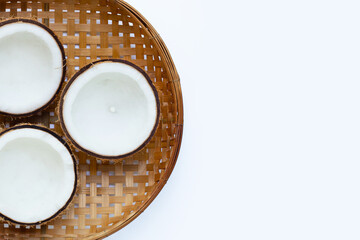 Half coconuts on wooden bamboo threshing basket on white background. Copy space
