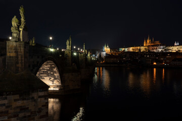 .Charles Bridge and lights from street lights are reflected on the surface of the Vltava River in the center of Prague at night in the Czech Republic