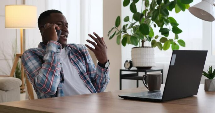 Businessman having fun talking on mobile phone while working on office laptop