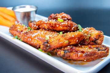 Delicious sweet spicy chicken wings piled on a plate makes the mouth water and the stomach growl.