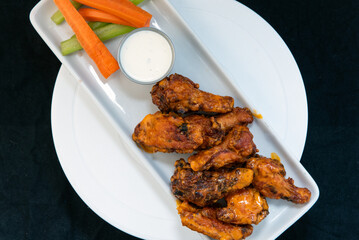 Overhead view of delicious sweet spicy chicken wings piled on a plate makes the mouth water and the stomach growl.