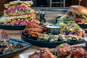 Full table of delicious meals straight from the grill including appetizer plate of tacos and stacked ahi tuna club sandwich.