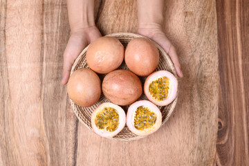 Fresh passion fruit in a basket holding by hand on wooden background, Tropical fruit, Top view