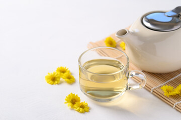 Obraz na płótnie Canvas Organic Chrysanthemum flower tea in a cup and teapot on white background, Healthy Herbal drink