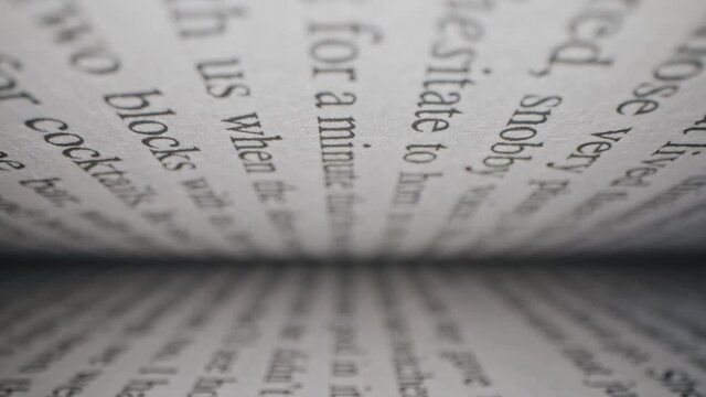 Macro view inside book slide dolly shot with laowa probe lens. Camera moves between paper book pages. Extreme close-up text printed in english
