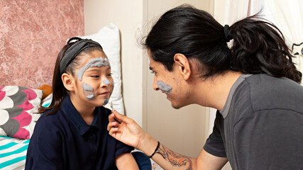 Naklejka premium Young man with a girl, playing putting on facial masks in a home spa