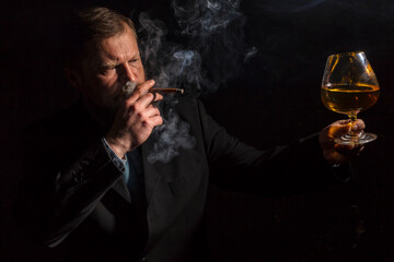 Solid confident bearded man in suit with glass of whisky and cigar with fume