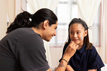 Young man with a girl, playing putting on facial masks in a home spa