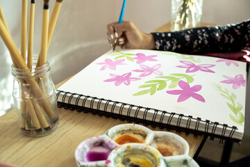woman hand painting with brush and watercolor, learning new activity at home