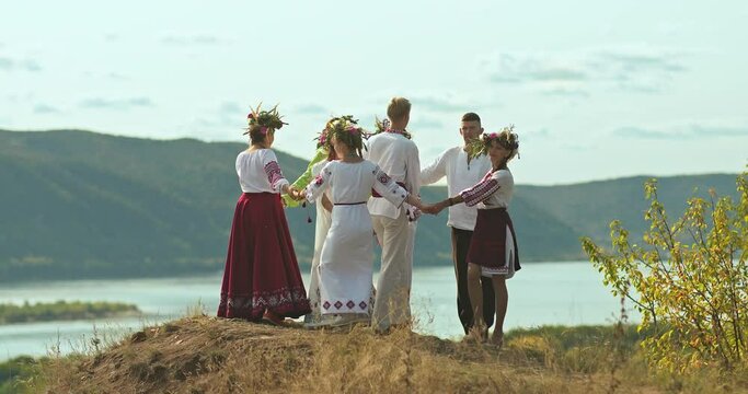 Group of young people in Slavic folk costumes lead a round dance on the mountain. Traditions and customs of the Slavic peoples. 4k, ProRes
