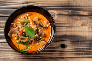 THAI BEEF RED CURRY. Thailand tradition red curry soup with beef  and coconut milk. Red Curry with ingredient in Black plate on woodden background., copy space