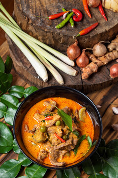 THAI BEEF RED CURRY. Thailand tradition red curry soup with beef  and coconut milk. Red Curry with ingredient in Black plate on woodden background.