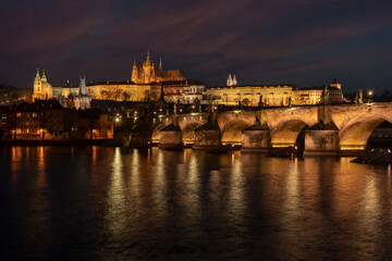 Fototapeta premium . prague castle and charles bridge and st. vita church lights from street lights are reflected on the surface of the vltava river in the center of prague at night in the czech republic
