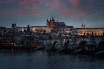 . prague castle and charles bridge and st. vita church lights from street lights are reflected on the surface of the vltava river in the center of prague at night in the czech republic
