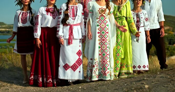 Group of singers in folk song costumes, beautiful rural landscape. Women in dresses with embroidery and wreaths of flowers on their heads, traditions and customs of the Slavic peoples. 4k, ProRes