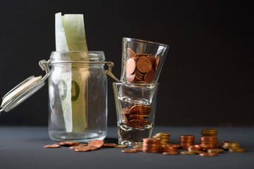 Concepts of finance, investing in assets with interest, dividend and profit. Coins are in the glass stacked on a black background.