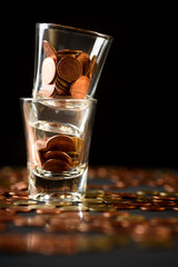 Concepts of finance, investing in assets with interest, dividend and profit. Coins are in the glass stacked on a black background.