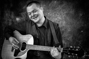 Obraz premium Mature musician plays acoustic guitar emotional studio portrait.