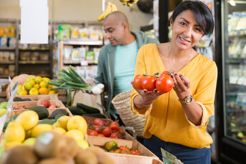 Man and woman picking ripe tomatoes together at grocery store