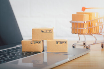 Brown paper boxs with laptop on wood table in office background.Easy shopping with finger tips for consumers.Online shopping and delivery service concept.