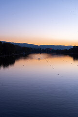 Lonely rowing boat sports in long canal training in calm sunset water with reflections and vibrant colors in Plovdiv, Bulgaria