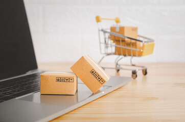 Brown paper boxs with laptop on wood table in office background.Easy shopping with finger tips for...