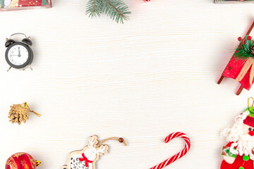 Fototapeta na wymiar sleigh of santa claus, boxes with gifts, toy santa claus, alarm clock, golden cones and spruce branch on a white wooden background