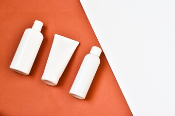 White blank tubes with cosmetics products on pink background.Cream tube, moisturizing foam and tonic water and green plant. Professional skincare concept. Copy space. Advertising.