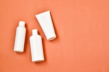 White blank tubes with cosmetics products on pink background.Cream tube, moisturizing foam and tonic water and green plant. Professional skincare concept. Copy space. Advertising.