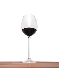 A large glass with red wine stands on a wooden table on a white background. Isolate, copy space, foreshortening and bottom view.