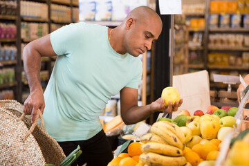 Buyer carefully selects ripe apples in a grocery supermarket