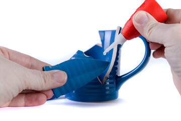Human hand holding a piece of blue ceramic mug to be fixed by glue