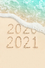 2020 and 2021 handwritten numbers on sand, beach and ocean wave on background