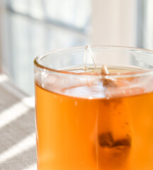 A beautiful glass filled with golden tea in the afternoon sunlight.