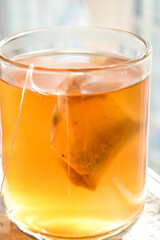 A beautiful glass filled with golden tea in the afternoon sunlight.
