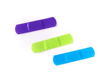 Three multicolored sticky bandage strips in parallel to each other