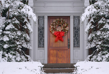 Christmas wreath on front door with elegant wood grain, with snow covered pine trees